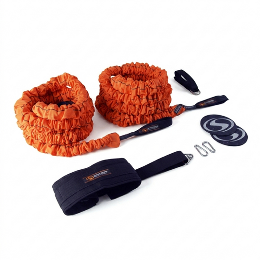 An orange elastic resistance band set with black handles, a black wrist strap, two black circular weight plates, and metal clips, displayed on a clean white background.