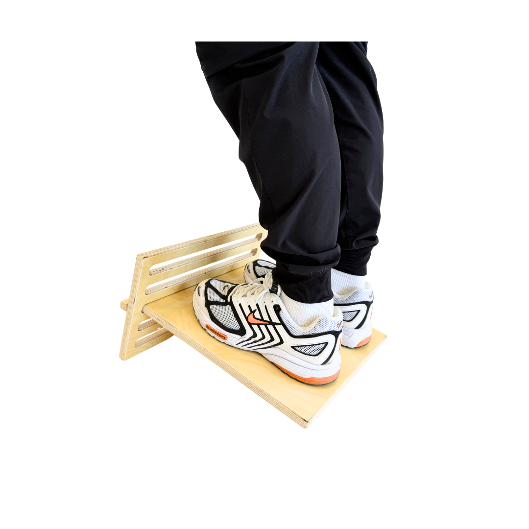 Person wearing black pants and white sneakers stepping onto a wooden platform