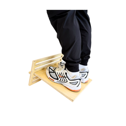 Person wearing black pants and white sneakers stepping onto a wooden platform