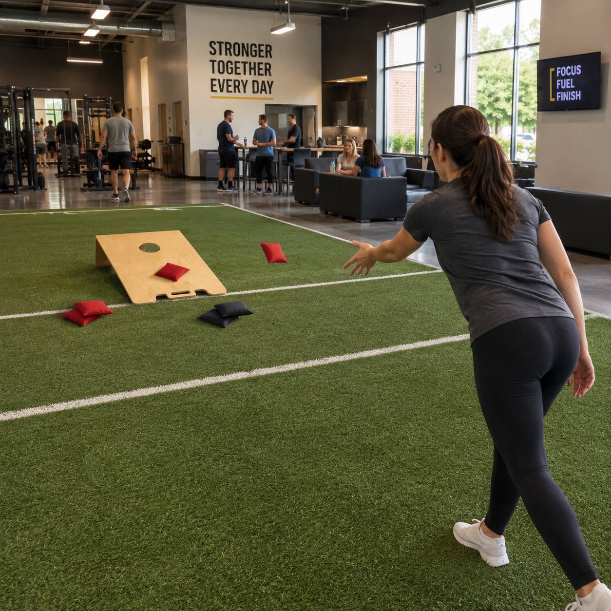 Woman throwing a bean bag at a cornhole board in a gym