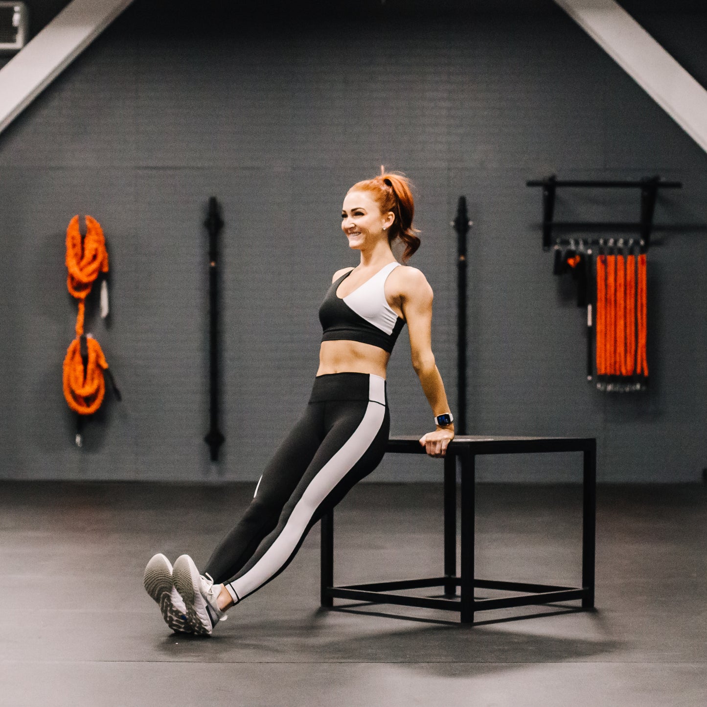 Woman exercising in a gym setting with fitness equipment in the background