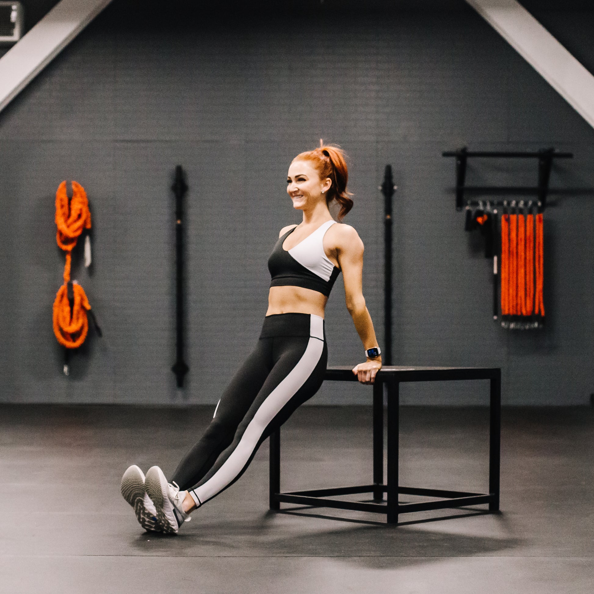 Woman exercising in a gym setting with fitness equipment in the background