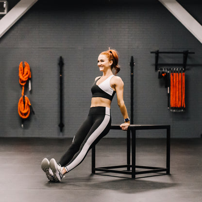 Woman exercising in a gym setting with fitness equipment in the background