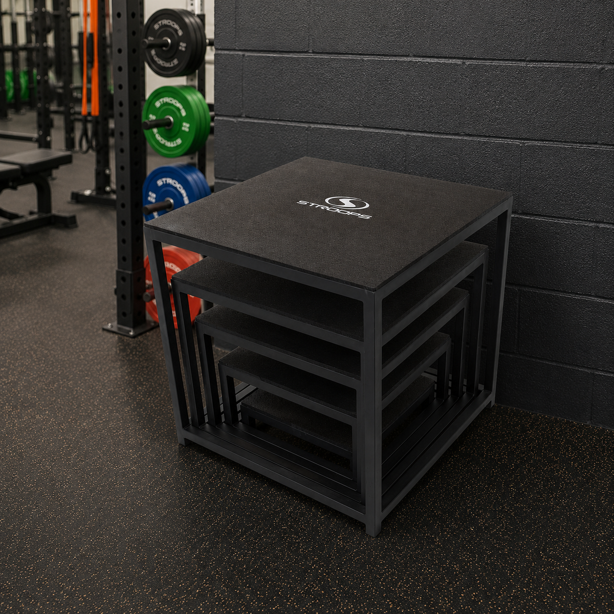 Stack of black plyoboxes with a logo in a gym setting