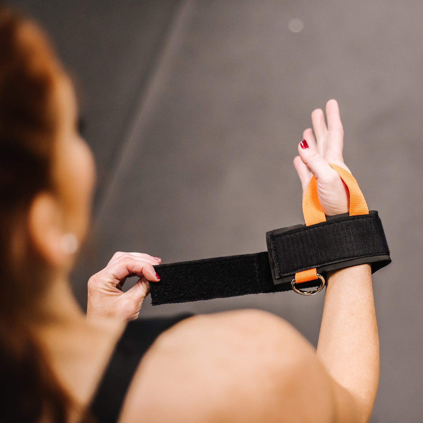 Person using a black and orange resistance band against a gray background