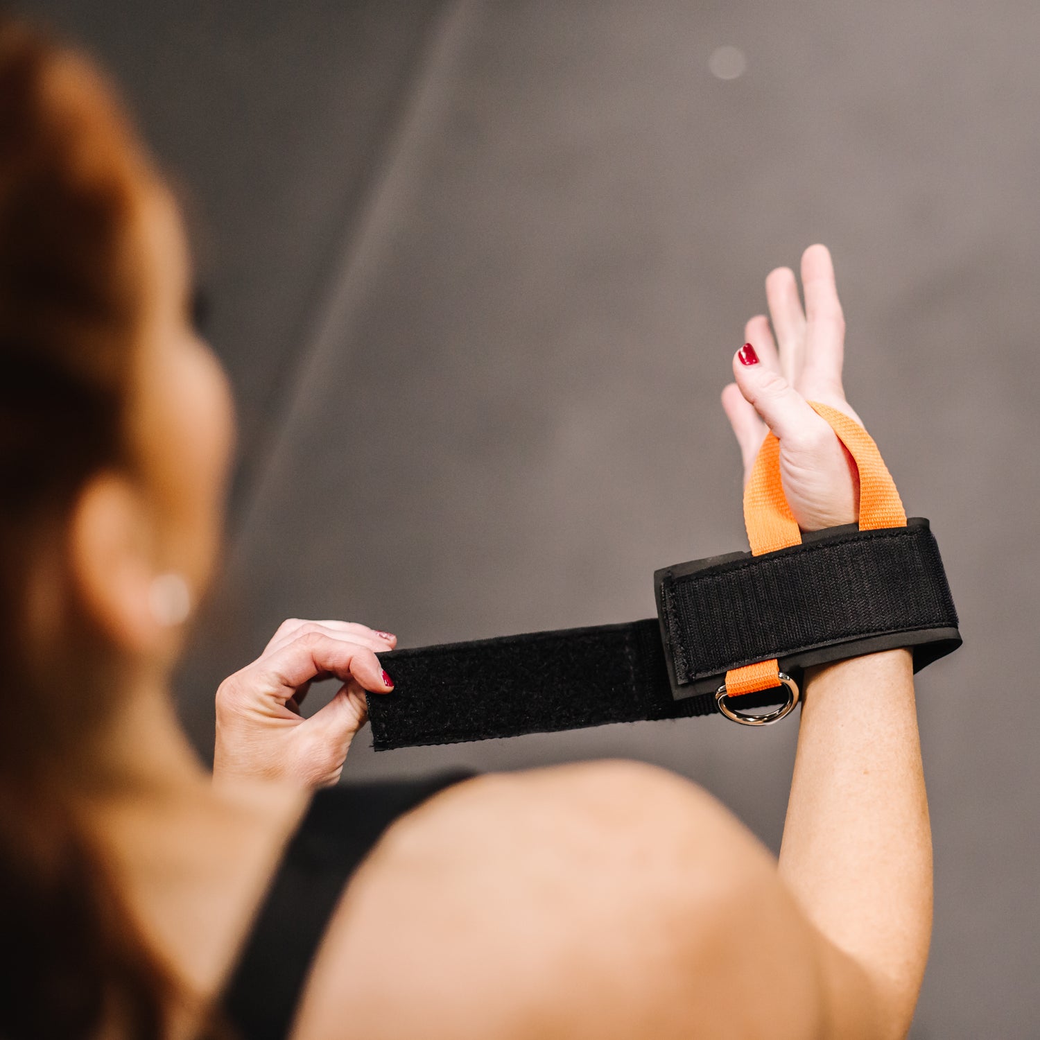 Person using a black and orange resistance band against a gray background