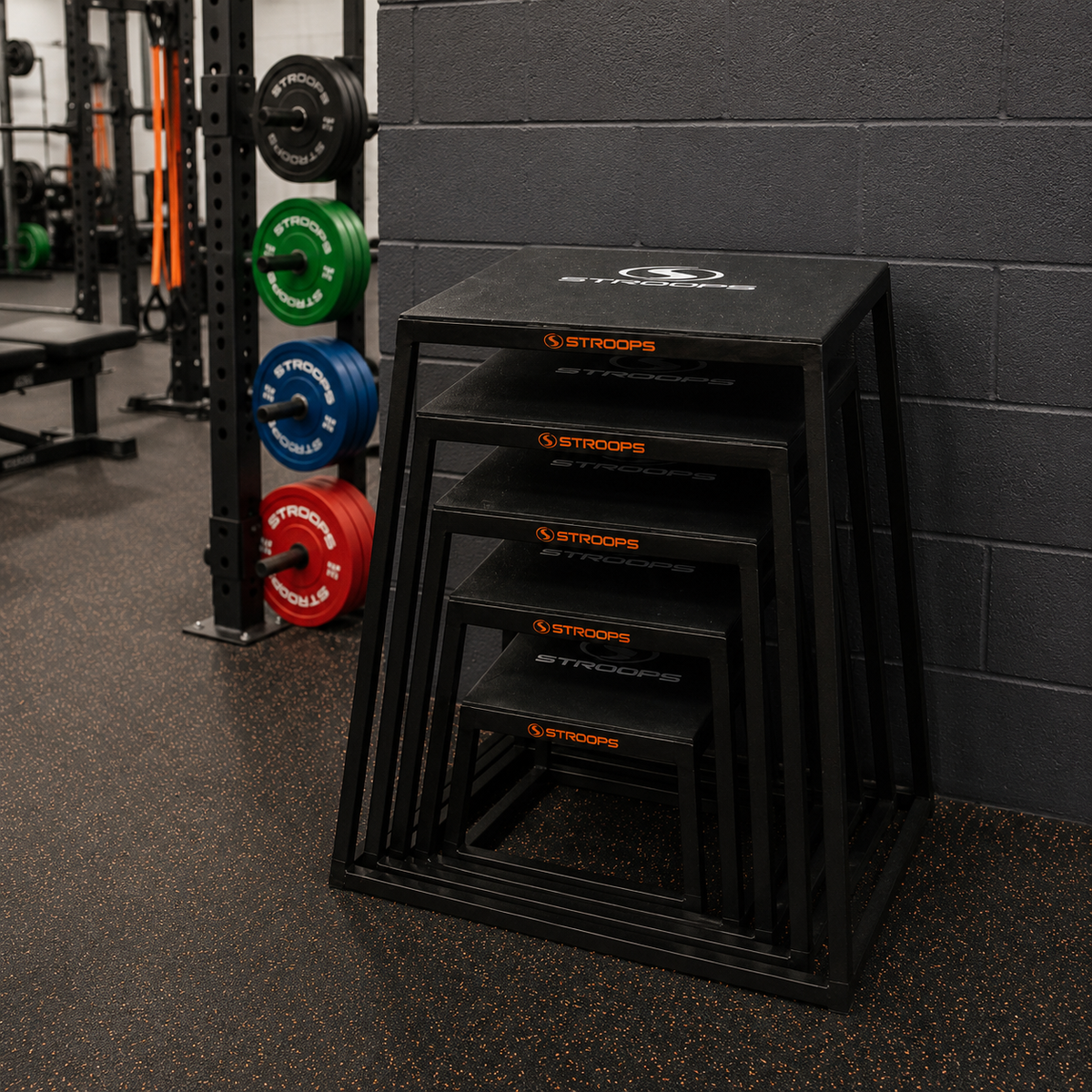 Stack of black plyoboxes with 'STROOPS' branding in a gym setting.