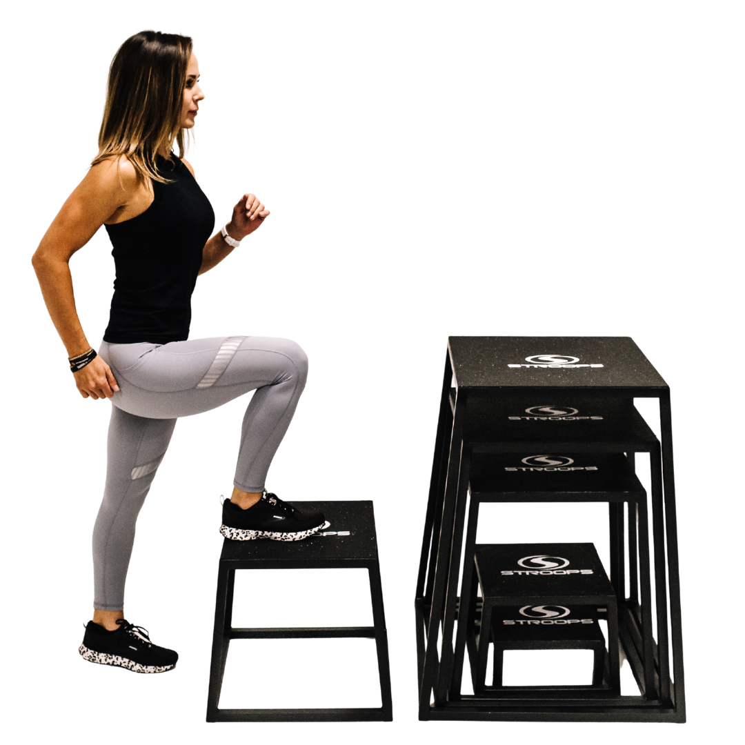 Woman using a set of black plyoboxes platforms on a white background