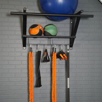 Gym equipment including a blue exercise ball, resistance bands, and a black bar on a gray wall.