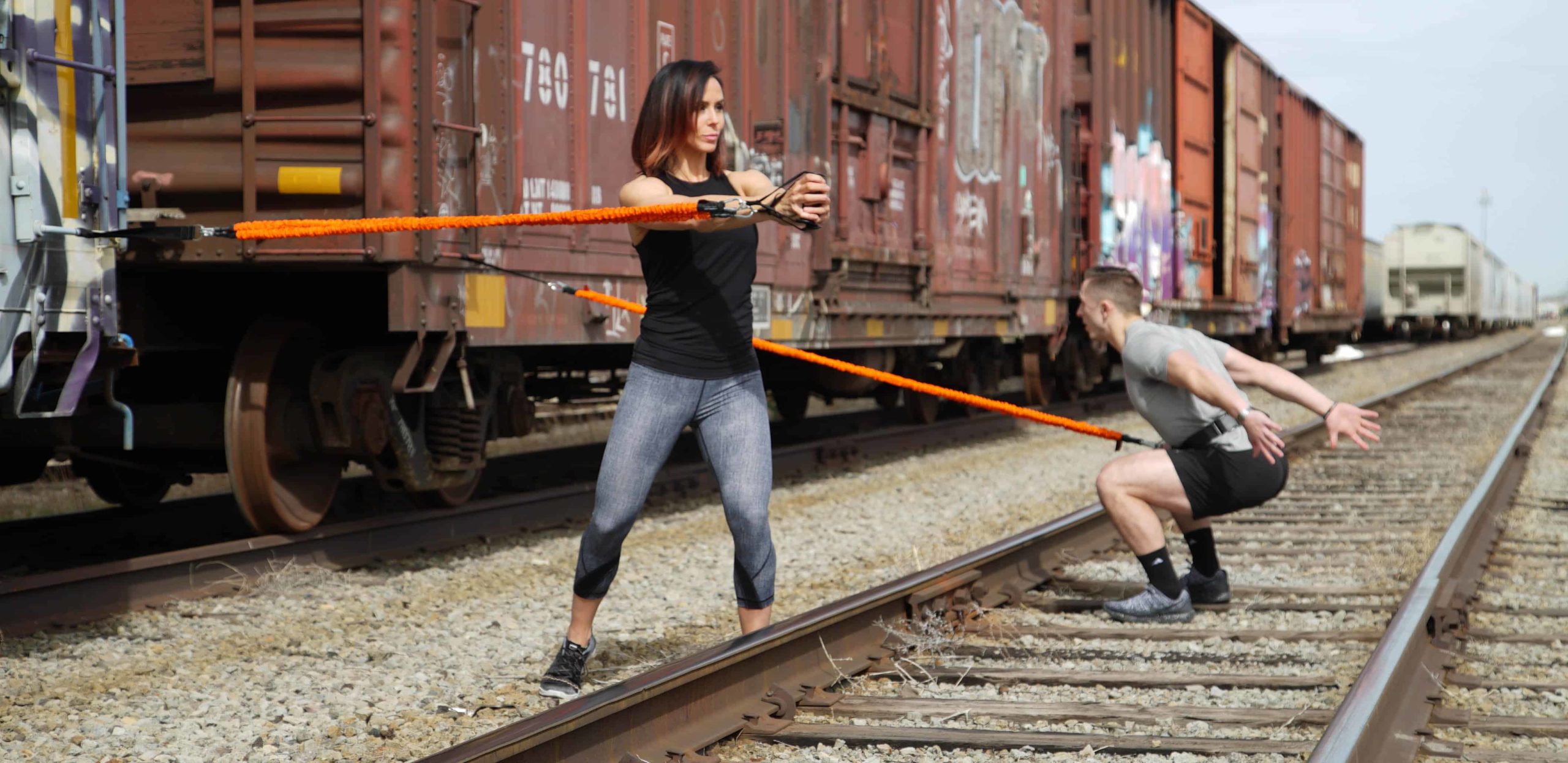 Stroops trainers doing a workout outside using Slastix connected to train cars