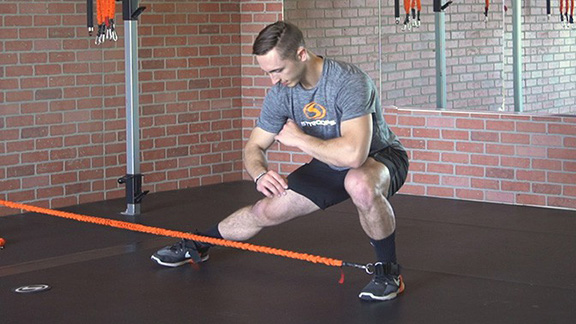 Stroops trainer Caysem doing HIIT lateral lunges with resistance bands.